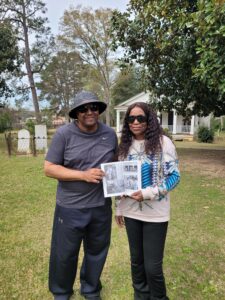 Mr. and Mrs. Greggory Phillips showing off a family photo found in one of our Orangeburg books we sell. They are standing in front of Dixie Hall the first library in Orangeburg, SC and on the grounds of the Pioneer Cemetery